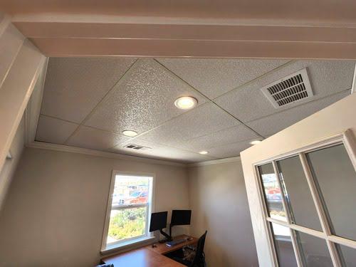 Installed acoustic ceiling tiles in a small office with recessed lights and vent