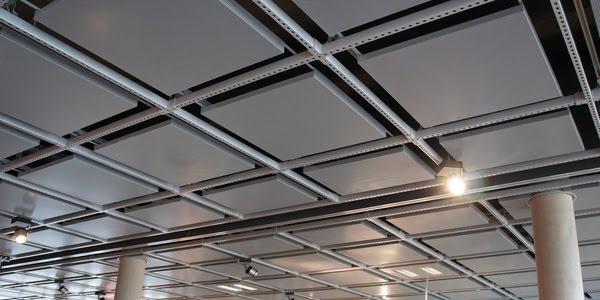 Modern acoustic ceiling tiles installed in a metal T-Bar grid system, featuring perforated panels and integrated lighting in a commercial interior