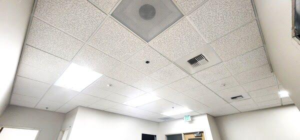 Drop ceiling (suspended ceiling) with acoustic tiles, recessed lighting, and air vents in a commercial hallway, ideal for noise control and maintenance access