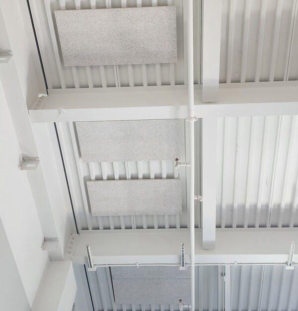 Acoustic ceiling panels installed on an industrial-style metal ceiling with exposed pipes