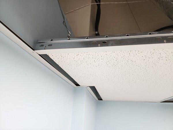 Drop ceiling with a misaligned or partially installed ceiling tile in a suspended grid system, revealing potential installation issues or needed maintenance