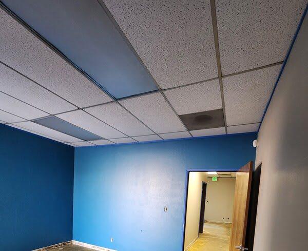 Suspended ceiling with stained tiles in a small office room