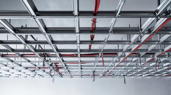 Black acoustic drop ceiling with integrated fluorescent lighting and ventilation panels, a result of modern acoustic ceiling tiles installation for commercial use