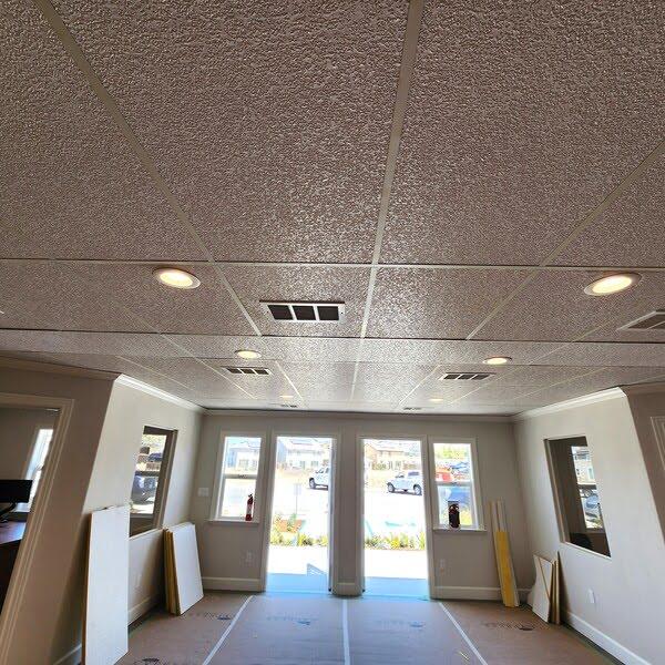 Textured acoustic ceiling tiles with recessed lighting in a bright entrance lobby