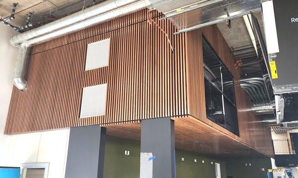 Custom vertical wood slat wall and ceiling panel installation with visible ductwork